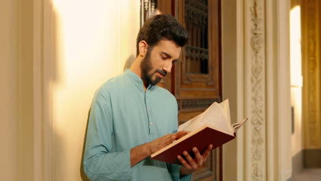 Handsome-Indian-man-in-light-blue-reading-a-book-outdoors