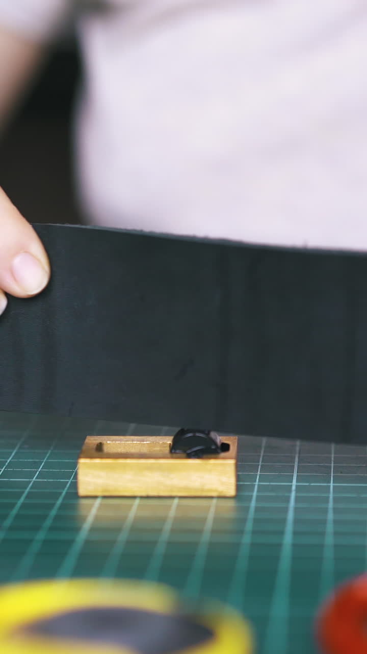 CU: Professional workshop girl worker colours black leather strip edges with pure copper in workshop close view