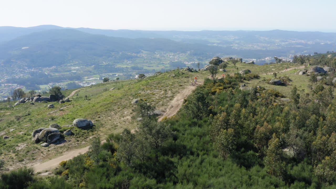 ciclistas de montaña reunidos en el sendero de la cima de la montaña portuguesa del norte - amplia toma panorámica aérea