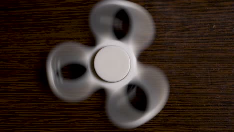 white fidget spinner spinning on wooden surface