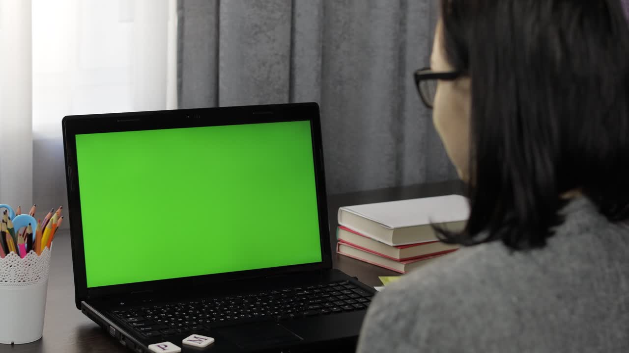 maestra haciendo llamada de video de educación a distancia en línea en la pantalla verde de la computadora portátil
