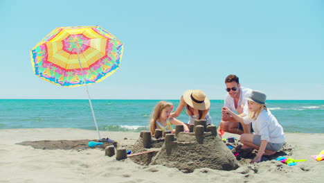 family building a sandcastle on the beach