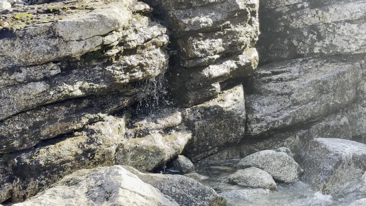 Sunlight illuminates a cascading waterfall over layered rocks