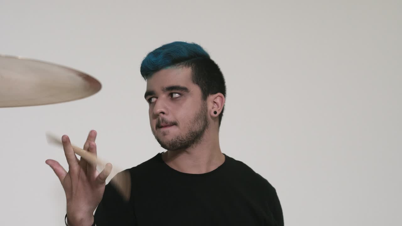 un tipo de cabello azul toca la batería.