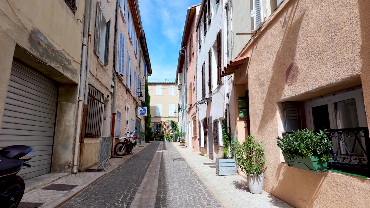 Una lenta carrellata in avanti attraverso un vicolo acciottolato stretto e tranquillo con edifici color pastello.