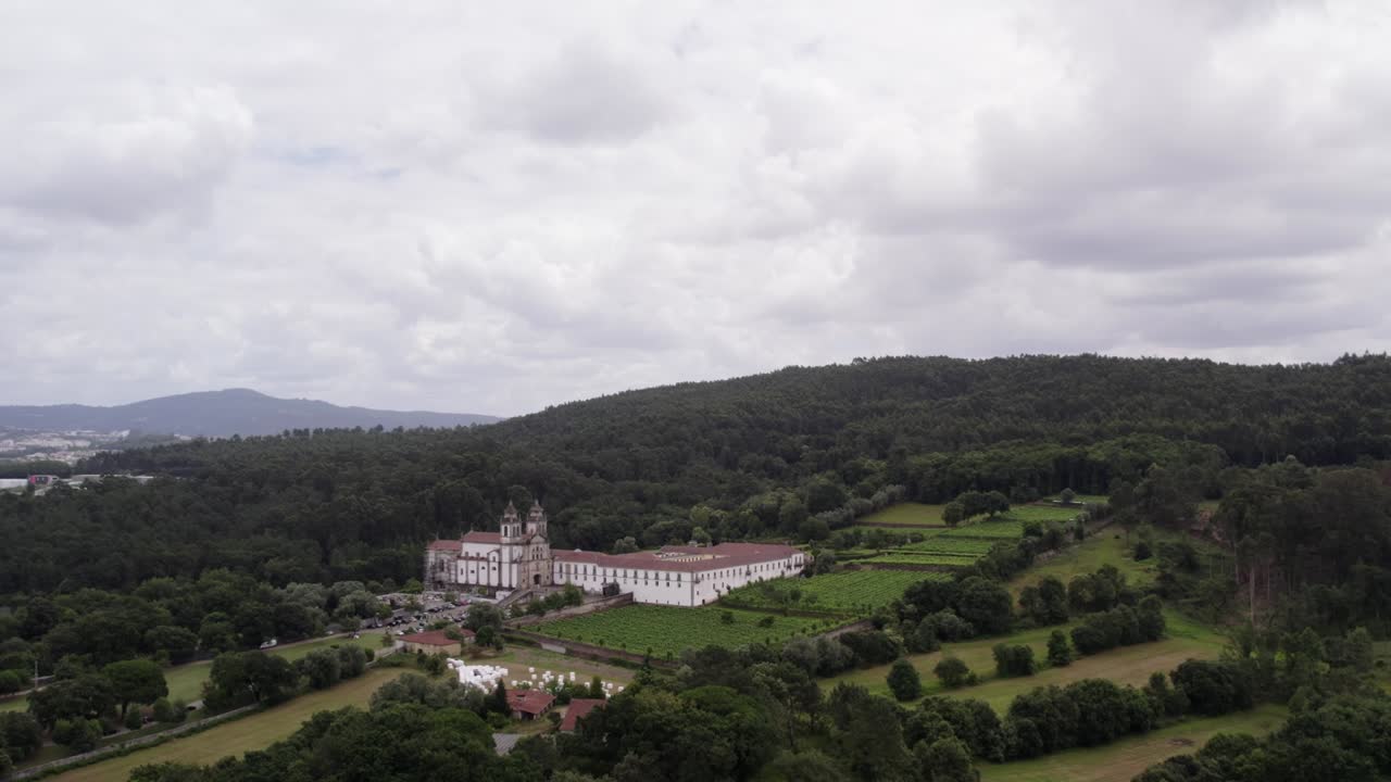 Ampia veduta aerea del Mosteiro de São Martinho de Tibães immerso nella campagna verdeggiante e nelle colline boscose nel Portogallo settentrionale.
