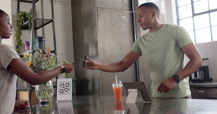 African American man and woman speaking at cafe, checking tablet while tapping reader and paying