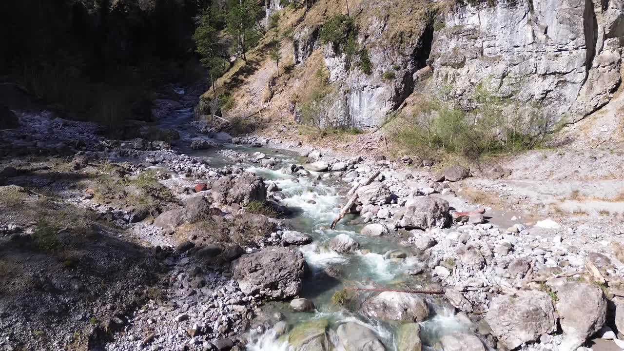 drone vuela sobre un río con agua turquesa cristalina en un valle montañoso con acantilados al lado en austria, europa