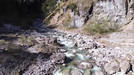 Drones-Vuelan-Sobre-El-Río-Con-Aguas-Cristalinas-De-Color-Turquesa-En-Un-Valle-De-Montaña-Con-Acantilados-Al-Lado-En-Austria,-Europa