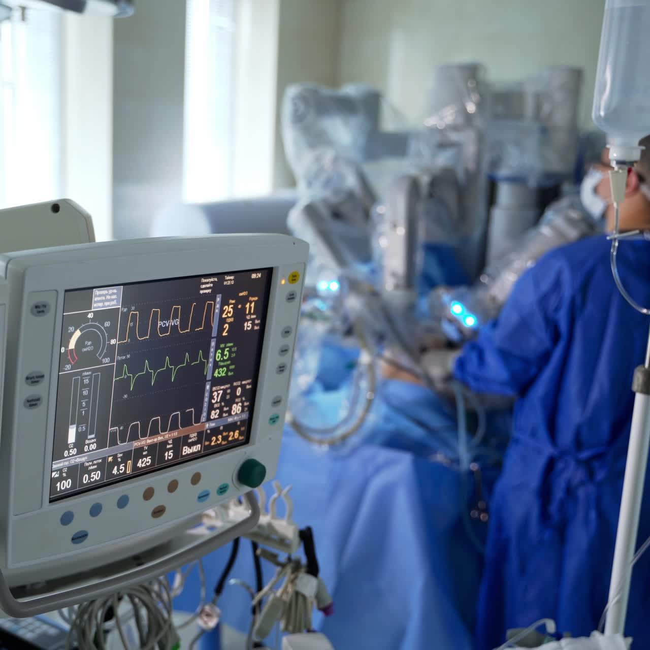 Screen showing the heartbeat of a patient during operation. Surgeon carrying out the operation with the help of robotic equipment in blur