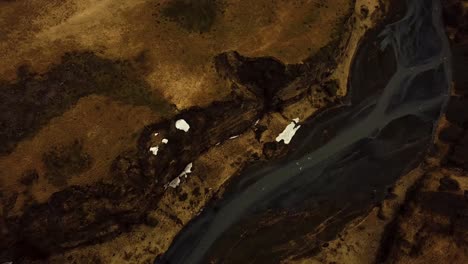 Aerial-landscape-view-of-a-river-flowing-through-Iceland-highlands-on-volcanic-black-sand