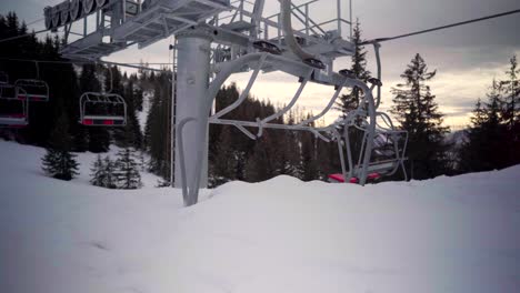 Abandoned-stopped-chairlift-buried-in-the-snow,-in-an-empty-ski-resort,-ski-slopes-deserted-during-Covid-19-coronavirus-pandemic,-in-mountains-in-winter