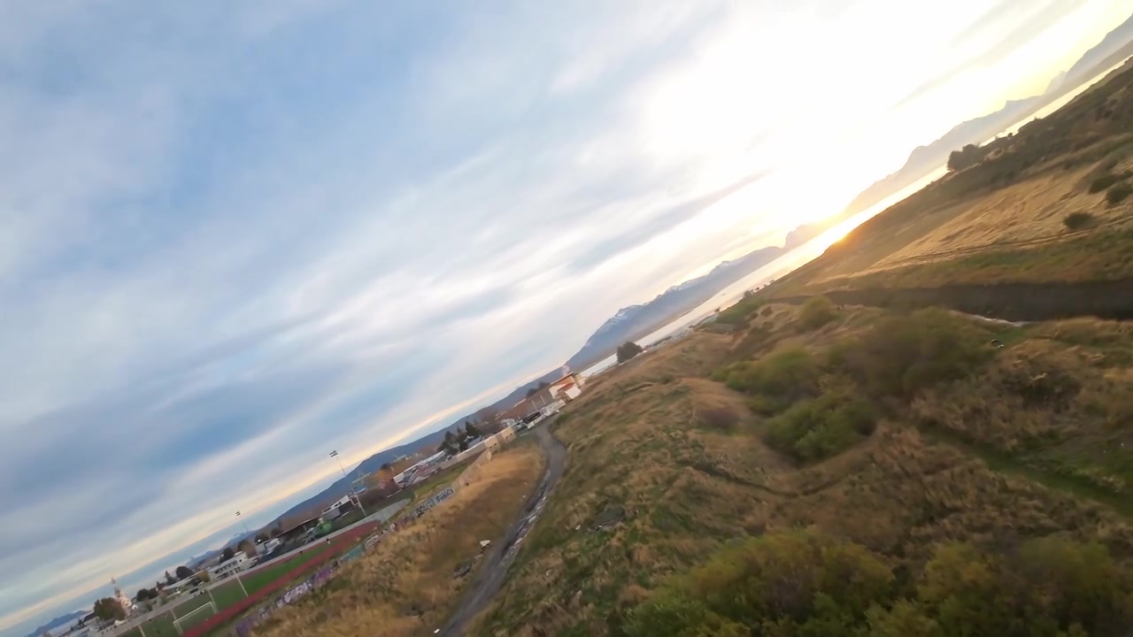Un ruscello tortuoso attraversa l'erba dorata della steppa patagonica, conducendo verso la città di Puerto Natales, Cile, con tetti visibili in lontananza sotto un cielo sereno.