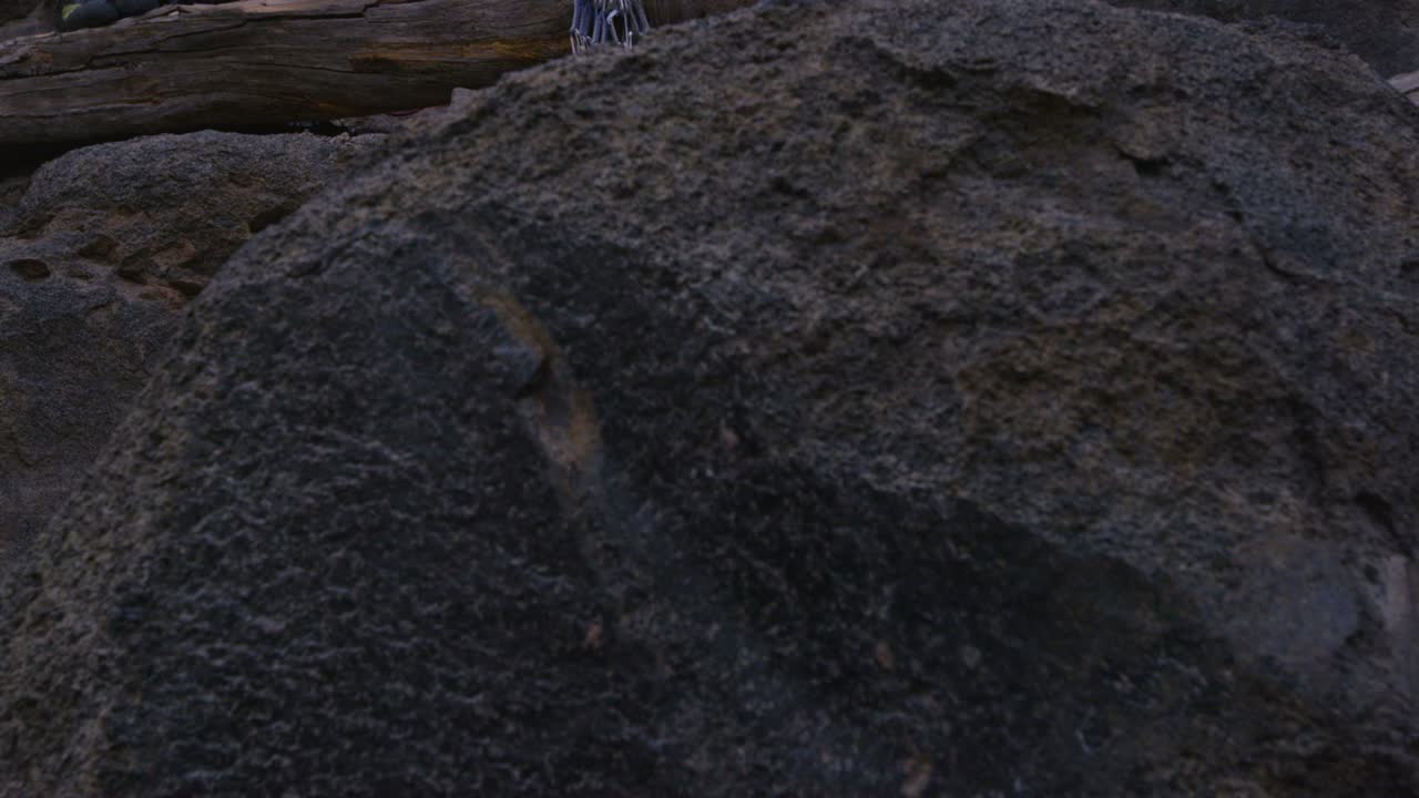 카메라가 위로 기울어져 암벽 바닥에서 준비하는 두 명의 암벽 등반가를 보여줍니다.