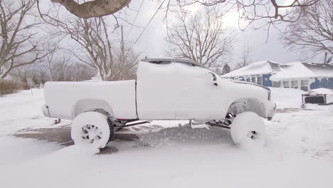 snow-covered pickup truck on driveway after storm in canada, handheld