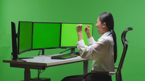 woman celebrating success on triple monitor green screen