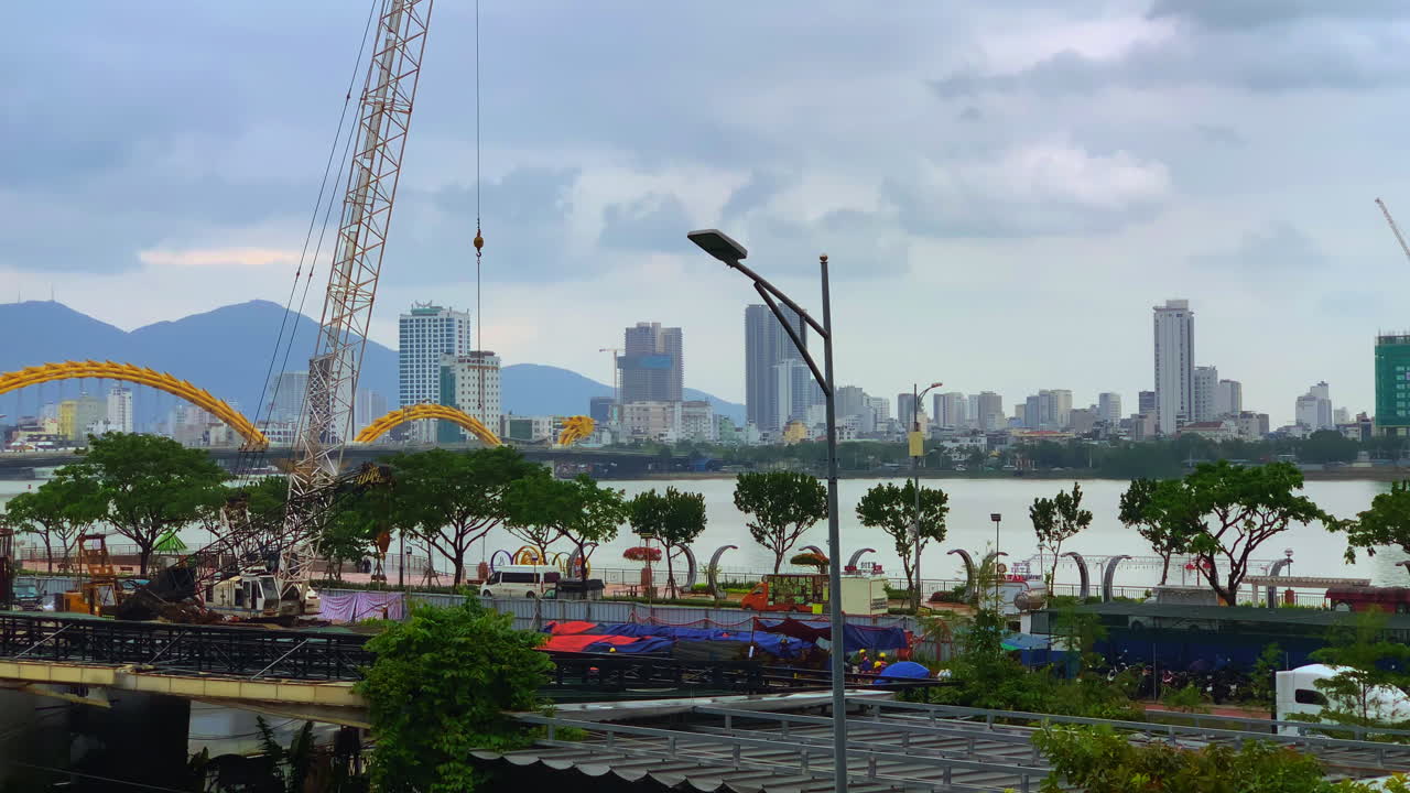 A view of Da Nang, Vietnam, showcasing the city skyline, Dragon Bridge, and a construction crane near the waterfront.