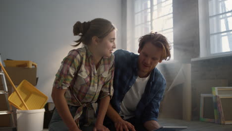 happy family enjoying draft of house renovation on floor. couple using tablet.