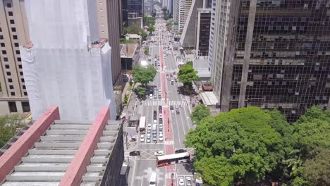 Main-commercial-street-of-Brazil,-the-Avenida-Paulista-in-Sao-Paulo-in-a-warm-afternoon-full-of-cars-slow-tilting-aerial-shot