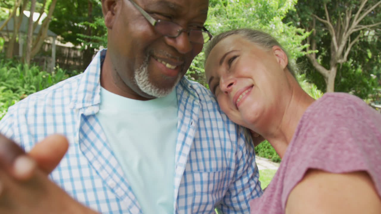 pareja feliz y diversa usando camisas y abrazándose en el jardín