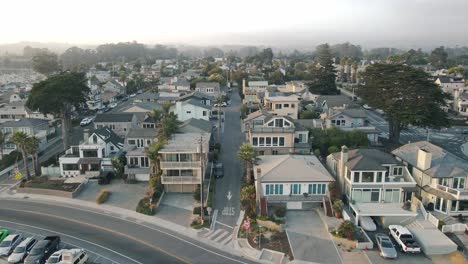 a slow-motion drone shot pushing into a peaceful, beachside santa cruz california community with expensive residential houses and short term rentals next to the small craft harbor at sunset