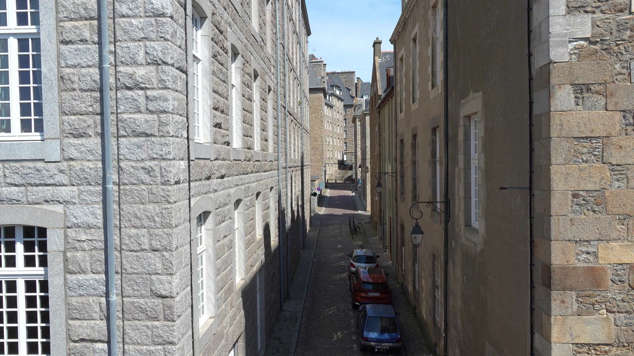 Stretta strada acciottolata fiancheggiata da edifici storici in pietra a Saint-Malo, Bretagna, Francia.