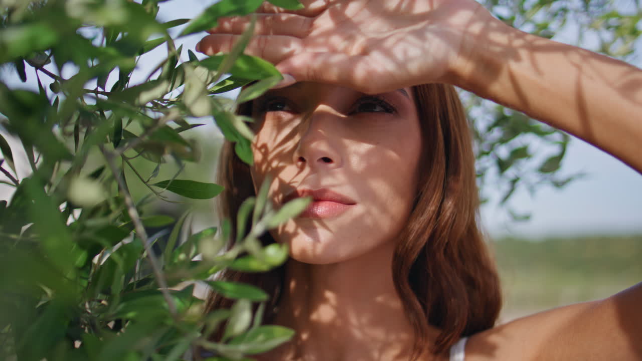 Closeup girl looking sunshine covering hand in garden. Portrait model posing