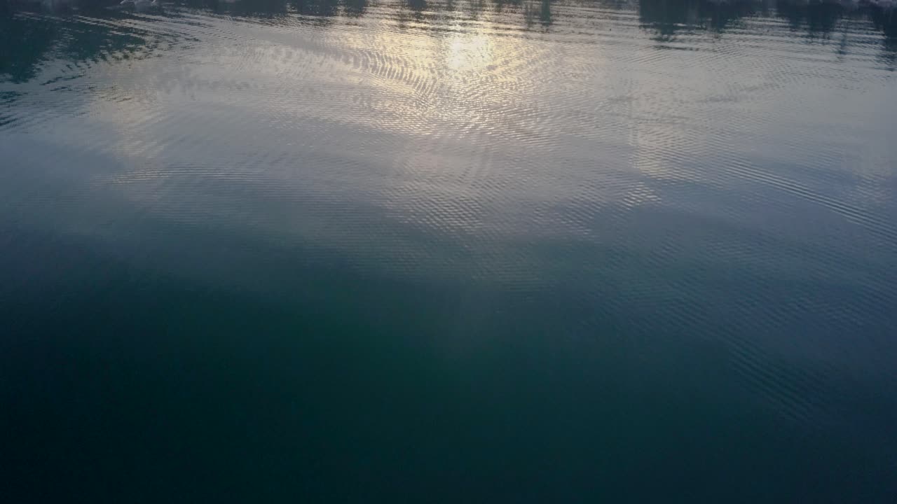 Aerial above beautiful turquoise waters to misty fishing village early morning in the Philippines -camera tracking and tilting up