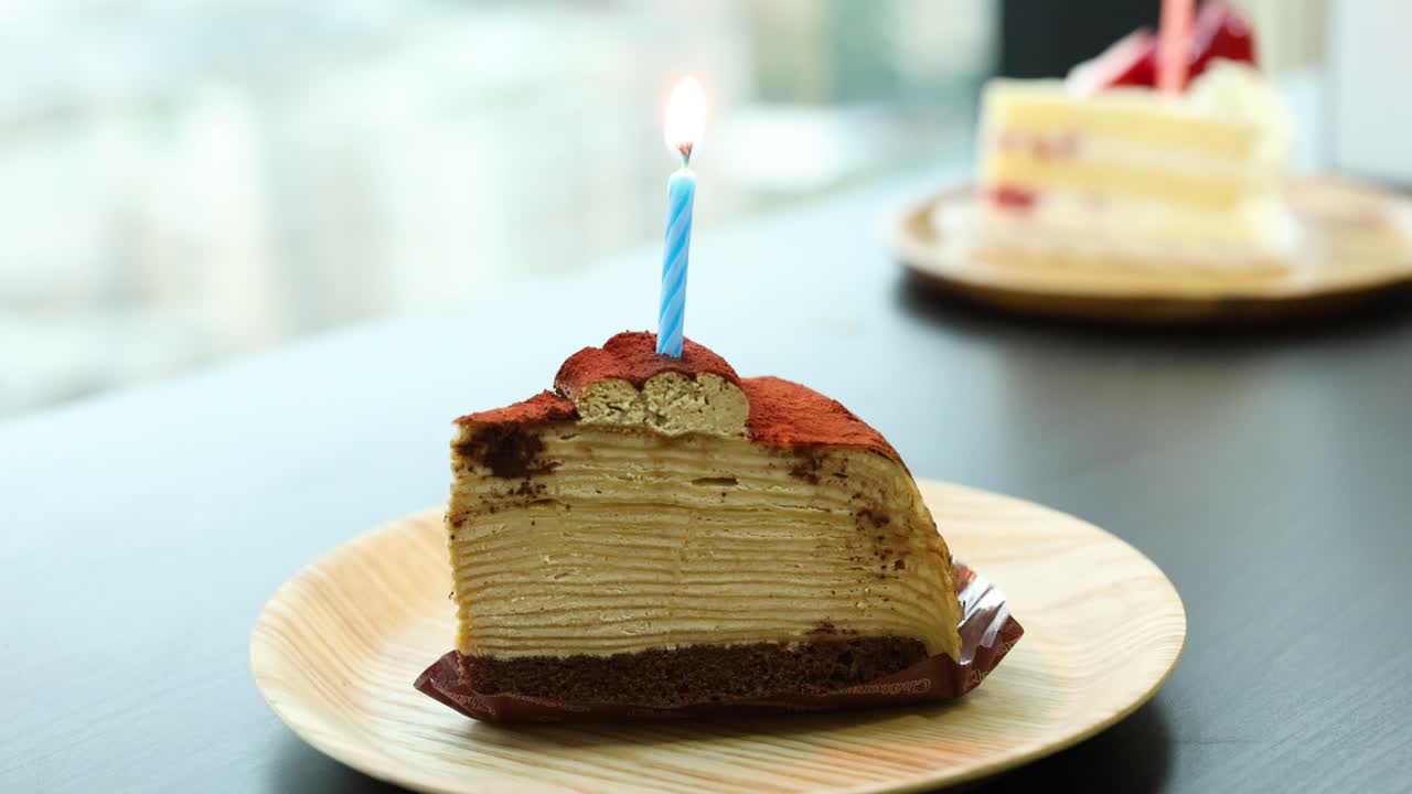 Tiramisu crepe cake slice with burning candle, natural daylight, shallow focus, static camera