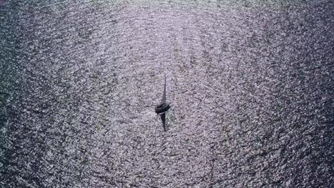 Aerial-shot-of-sailboat-passing-through-sun-reflection-on-Lake-Leman,-Switzerland