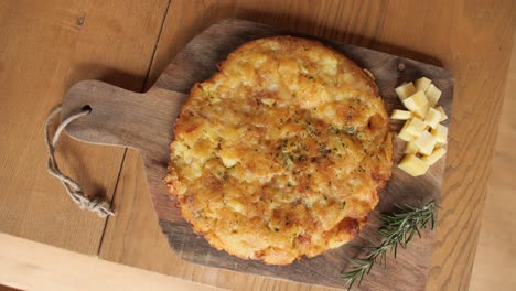 top down spinning shot of omlette made of cheese, potatos and eggs, decorated wooden plate