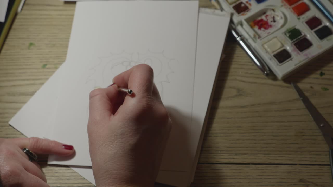 Top down, close up of painting set and female hands painting a Christmas card