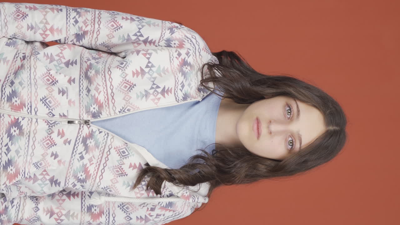 둔한 표정으로 카메라를 바라보는 젊은 여성의 수직 비디오.