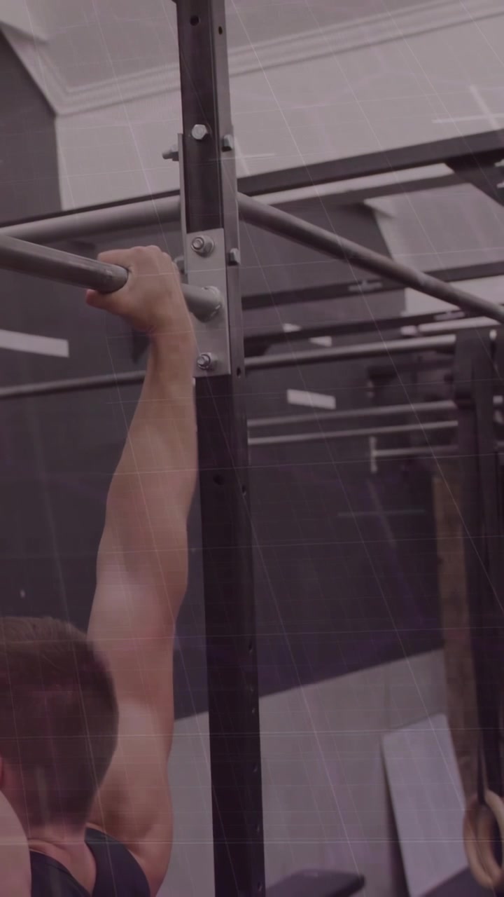 Man in black tank top performing pull-up on horizontal bar at gym, rings, copy space