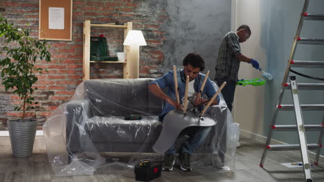 un hombre afroamericano pinta la pared, un hermano monta la silla.