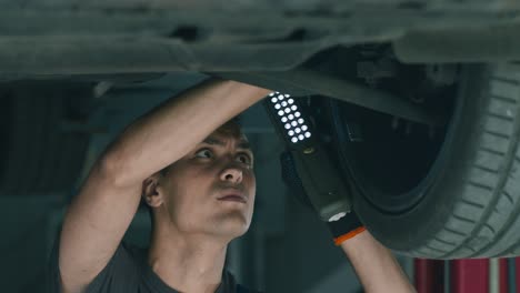 mecánico que inspecciona el tren de aterrizaje del automóvil
