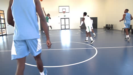 multiracial male basketball players playing basketball, passing and throwing basketball in gym