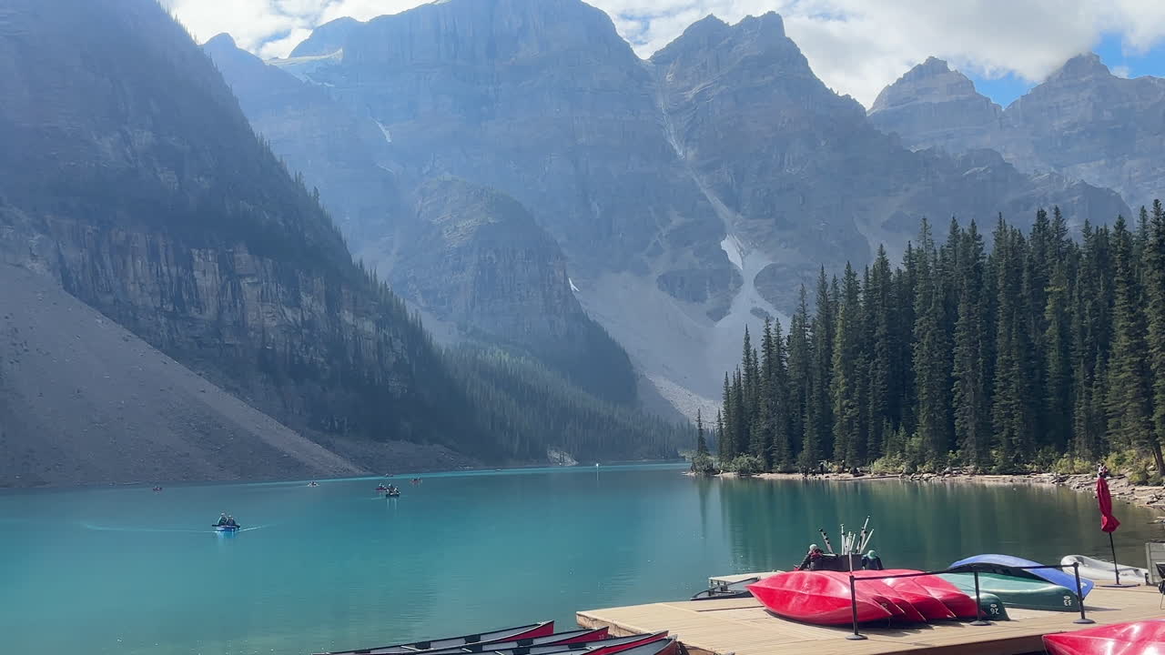Boats gliding gracefully across the pristine blue-green waters of Moraine Lake, nestled in the heart of Banff, Canada.