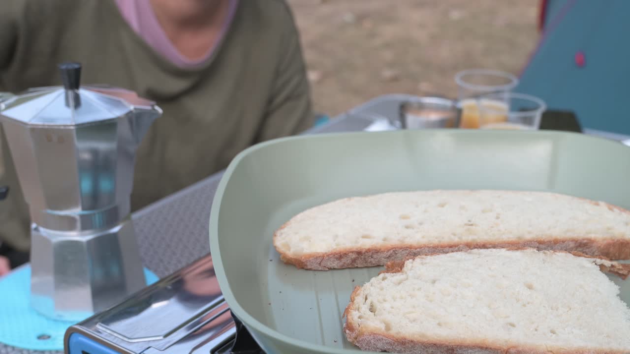 Camper preparing toasted bread slices for breakfast outdoors