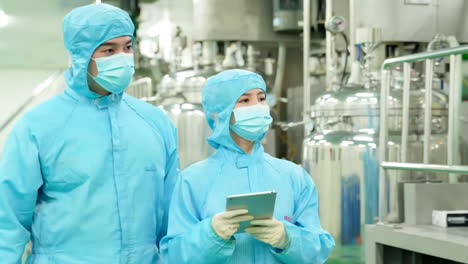 making medicine factory, medical staff in protective uniform work using tablets to walk and communicate with pharmaceutical facilities at drug manufacturing plant