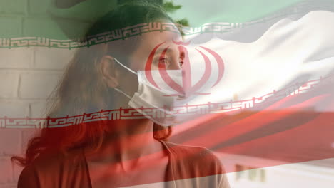 bandera iraní ondeando contra una mujer con máscara facial