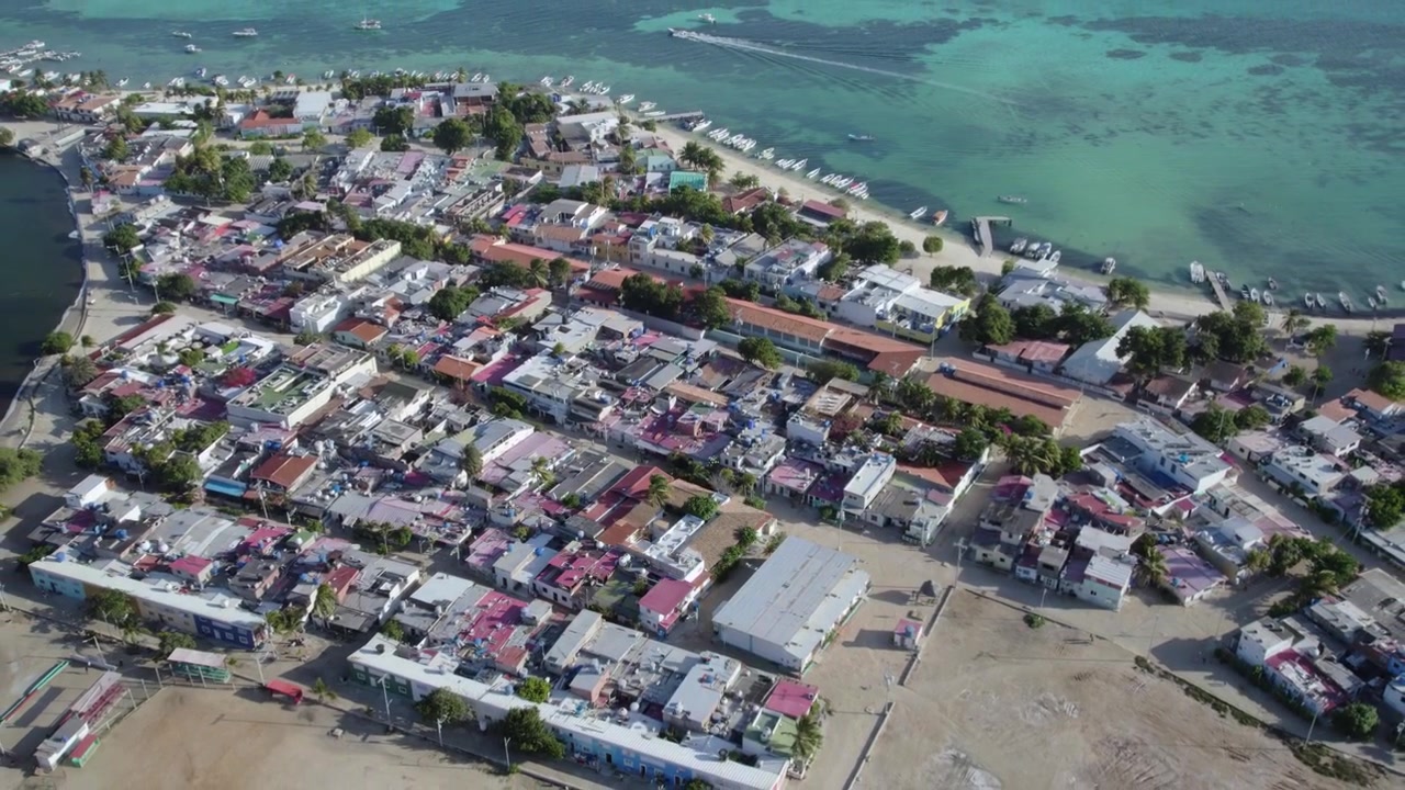 Ripresa con drone rivela un villaggio costiero con tetti colorati e barche lungo il mare turchese