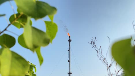 Gasfackel-Der-Erdölraffinerie-Loderndes-Feuer-Strömt-Aus-Dem-Schornstein-Dicken-Schwarzen-Rauch-In-Den-Blauen-Himmel