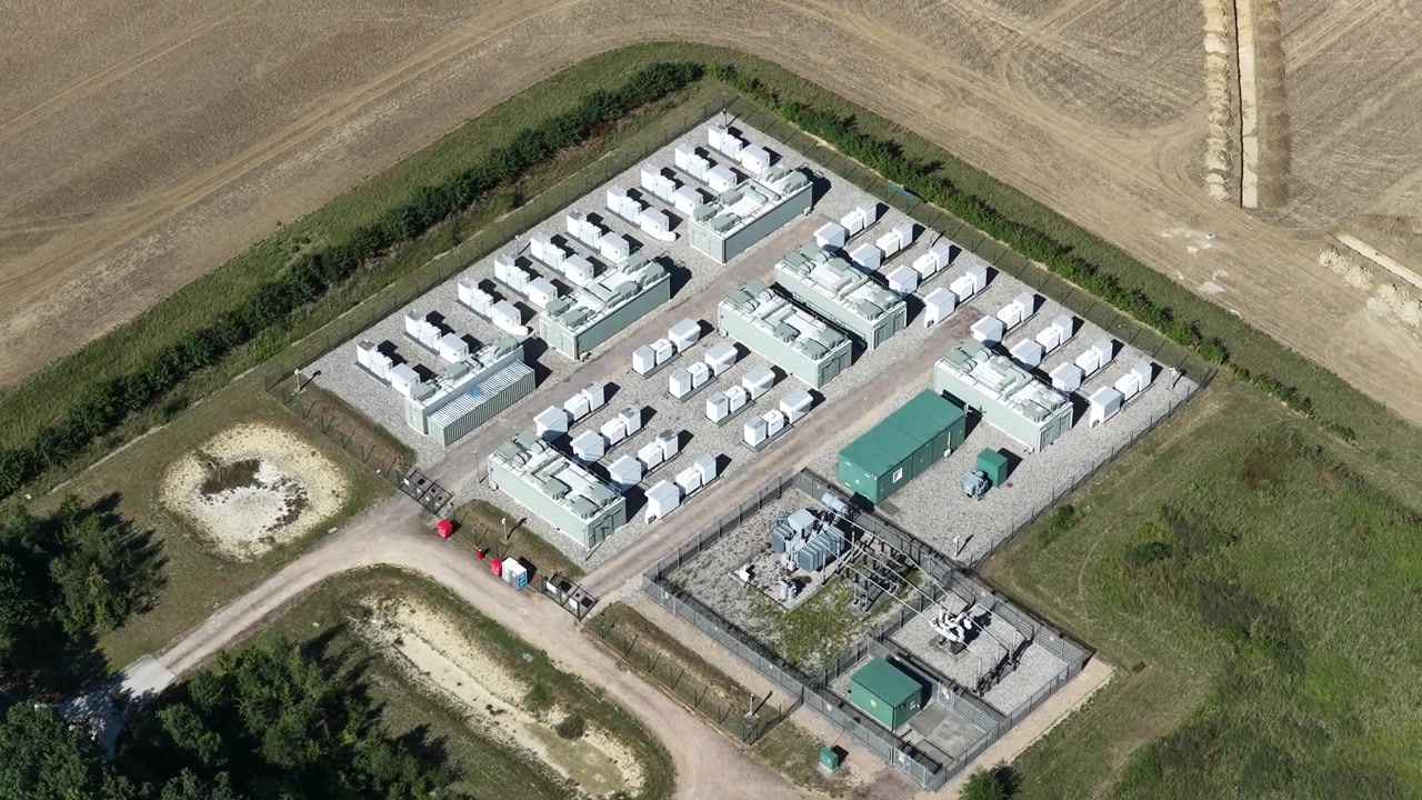 Vista aerea di un sistema di accumulo energetico a batterie accanto a una sottostazione ad alta tensione, a supporto della stabilità della rete, del bilanciamento del carico e della prevenzione della congestione nella rete elettrica.