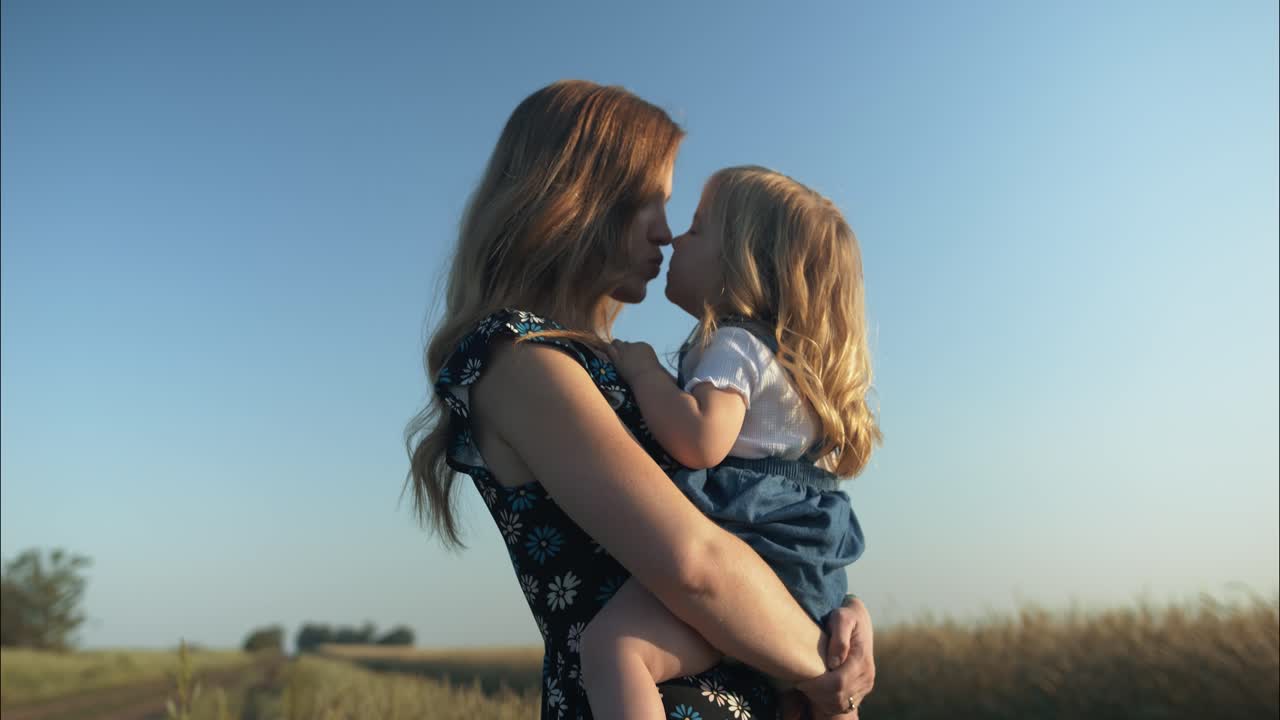 Mutter und Tochter teilen einen zärtlichen Moment in einem Weizenfeld