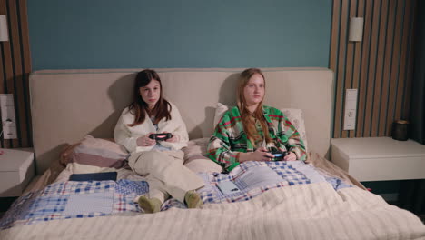 teenagers playing video games on bed