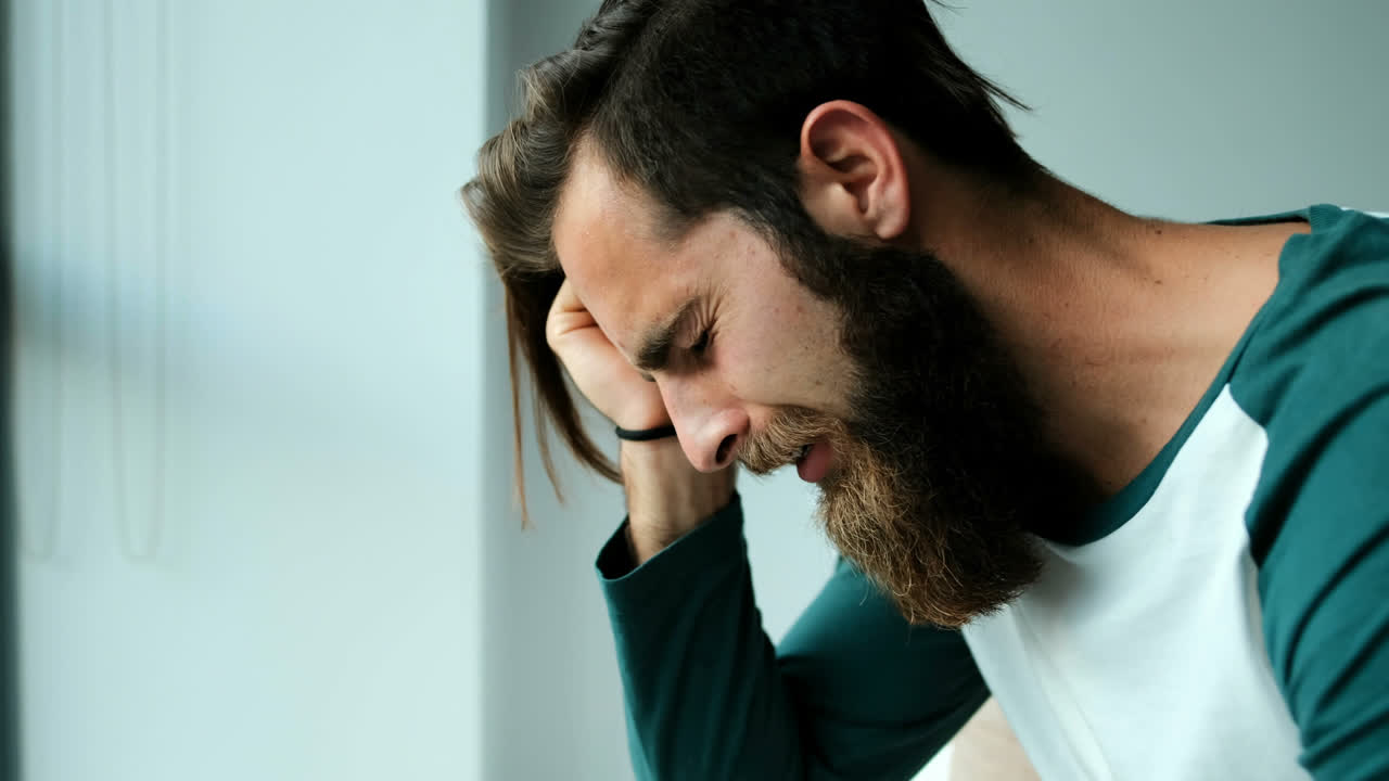 Uomo che piange mentre è seduto su un letto 4k
