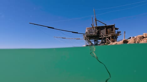 Split-underwater-view-of-trabocco-or-trabucco-at-Punta-Penna-beach-in-Costa-dei-Trabocchi-,-Abruzzo-in-Italy