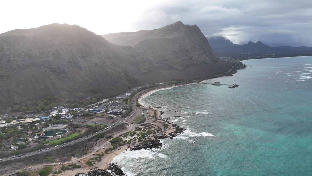 Drone in avvicinamento a Oahu, Hawaii, con un raggio di sole drammatico al tramonto che illumina la cima delle montagne. Scenario di un'isola tropicale, costa e vivaci viste sull'oceano. Filmato aereo cinematografico.