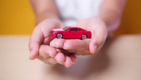 Hand-woman-protect-with-her-hands-a-red-car,-concept-for-insurance,-buying,-renting,-fuel-or-service-and-repair-costs